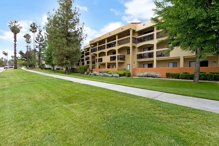 A condo building with balconies and a grassy lawn. 
