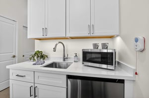 Kitchenette in an assisted living residence at The Terraces of Los Gatos with white cabinetry, sink, and appliances.