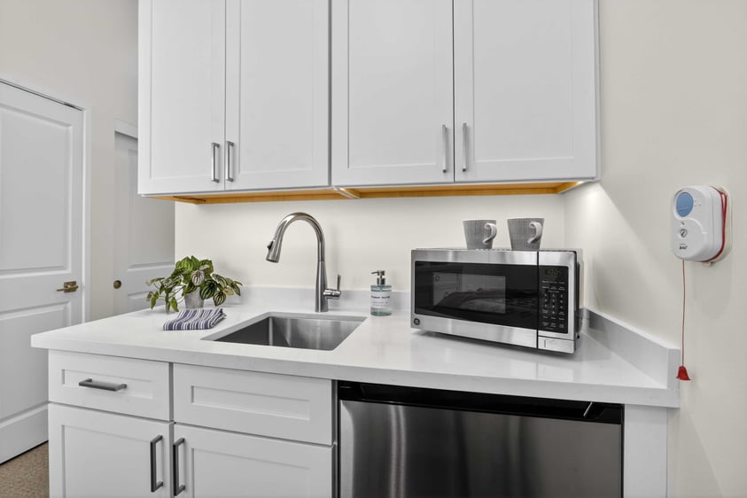 Kitchenette in an assisted living residence at The Terraces of Los Gatos with white cabinetry, sink, and appliances.