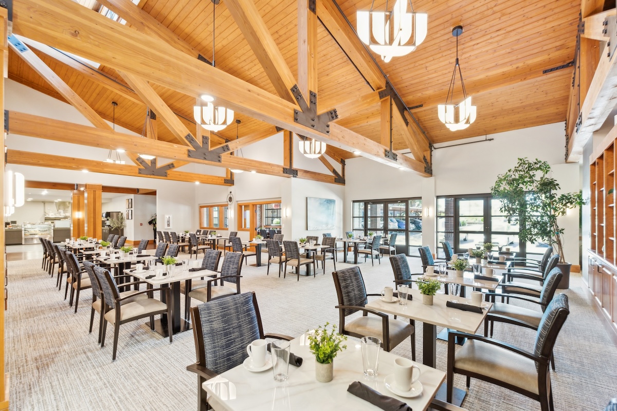 Spacious dining area with wooden vaulted ceiling, numerous tables, and large windows