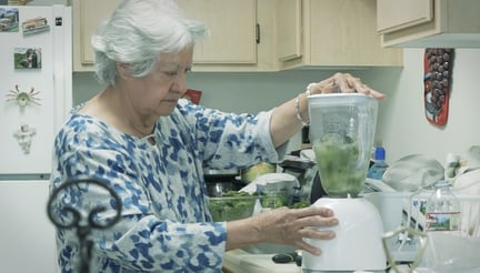 senior using blender in kitchen