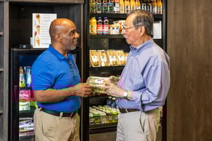 Residents talking together while holding prepared food items in a café or market area