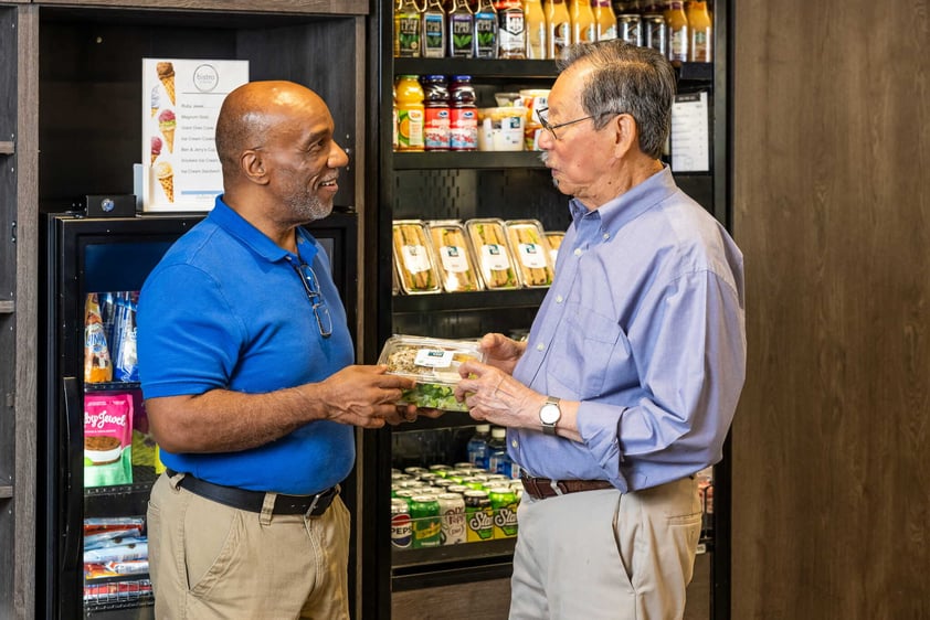 Residents talking together while holding prepared food items in a café or market area
