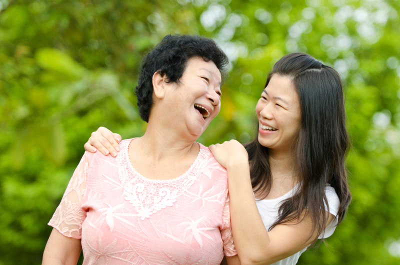 A joyful mother and daughter share a laugh outdoors