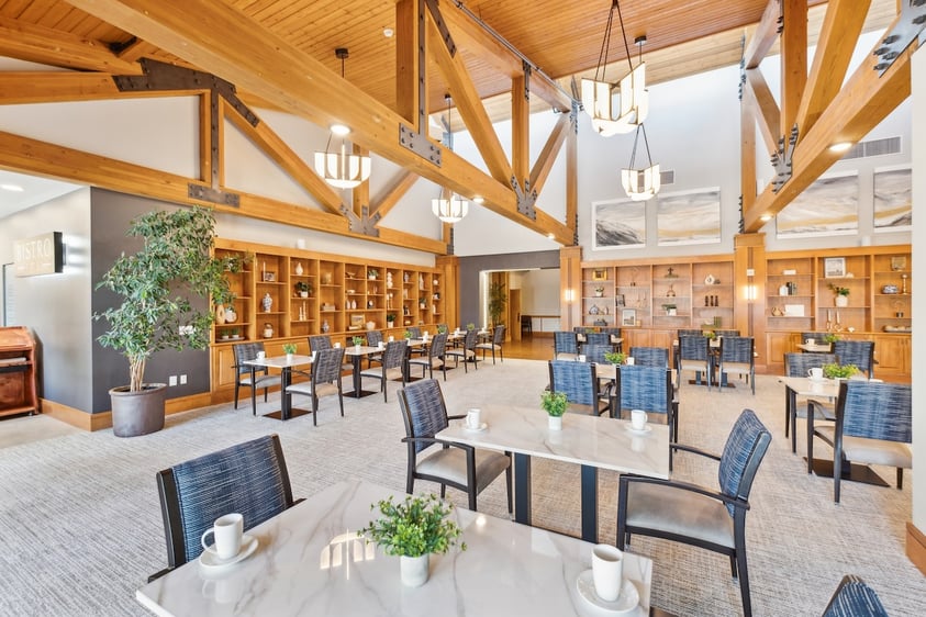 Dining area with wooden beams, marble-topped tables, and decorative bookshelves
