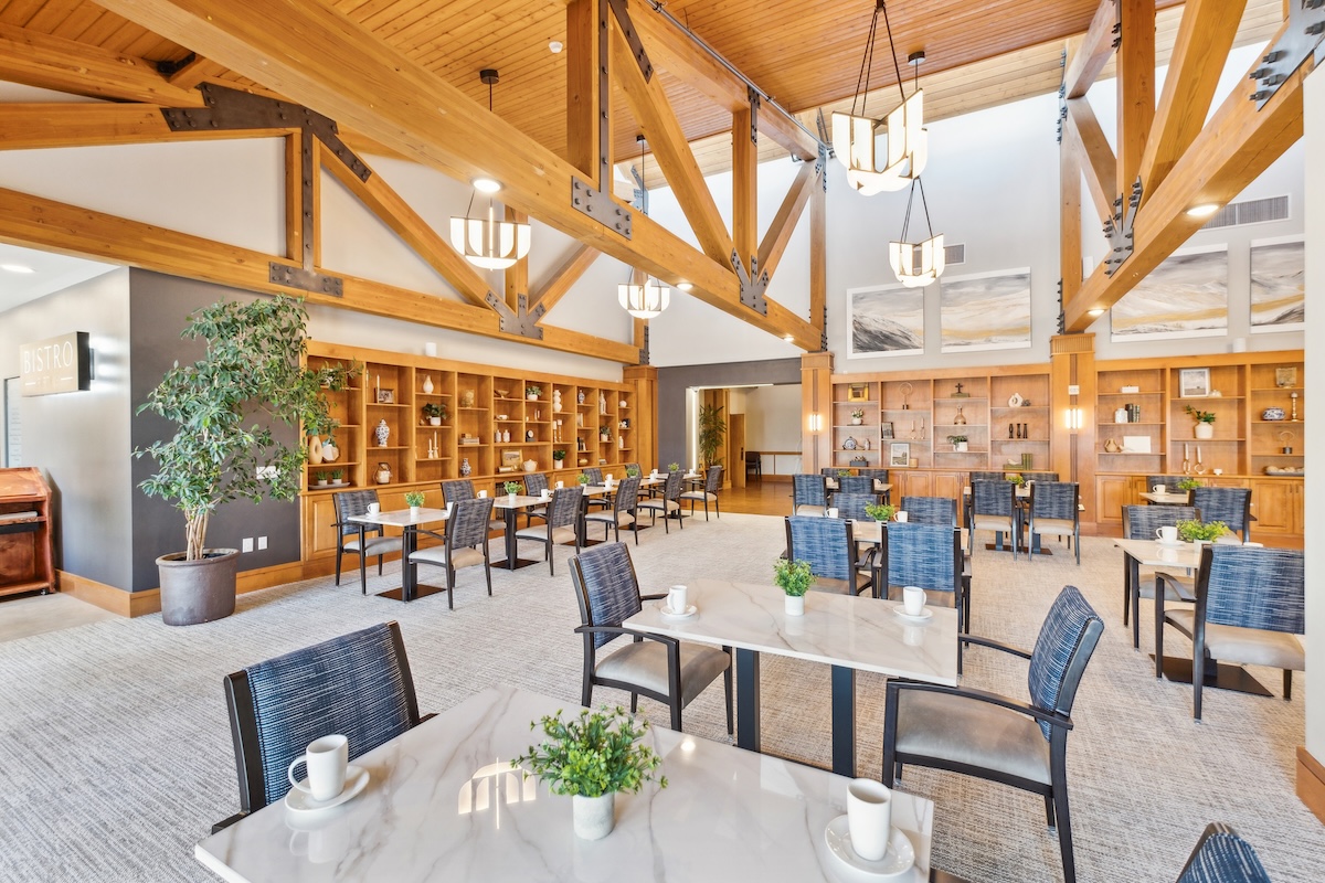 Dining area with wooden beams, marble-topped tables, and decorative bookshelves
