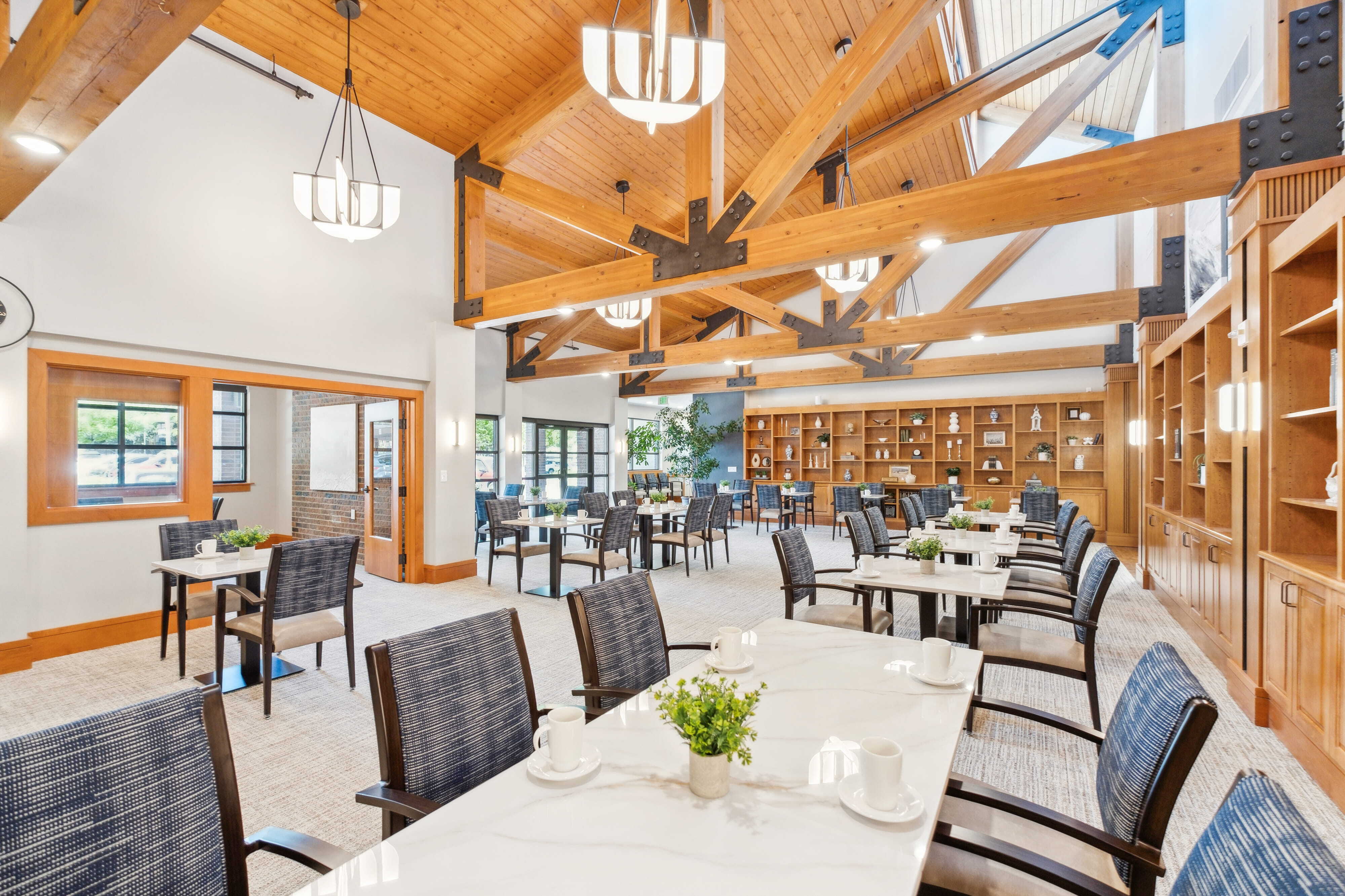 Bright dining room at The Terraces at Summitview with tables, chairs, and wood beam ceilings.