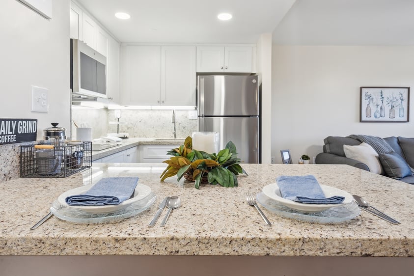 Rosweood kitchen with granite island set for two, stainless steel appliances, and a decorative centerpiece