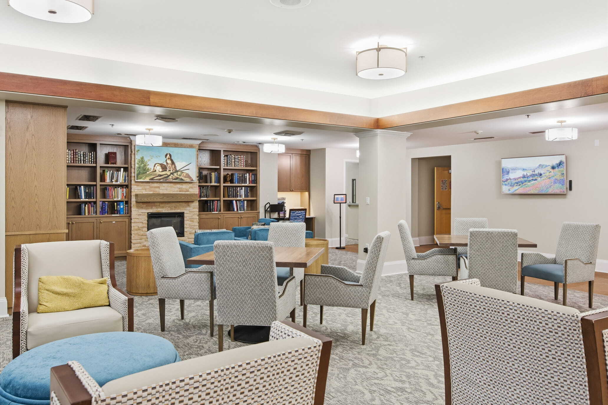 Residents select freshly prepared meals at the Bistro at the Park, with staff serving food behind a glass counter in a bright dining space.