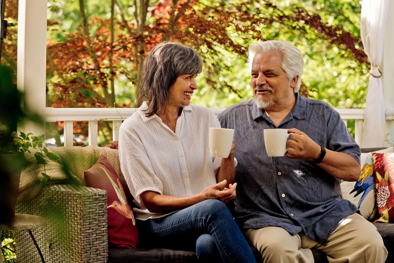 A senior couple drinking coffee on the porch.