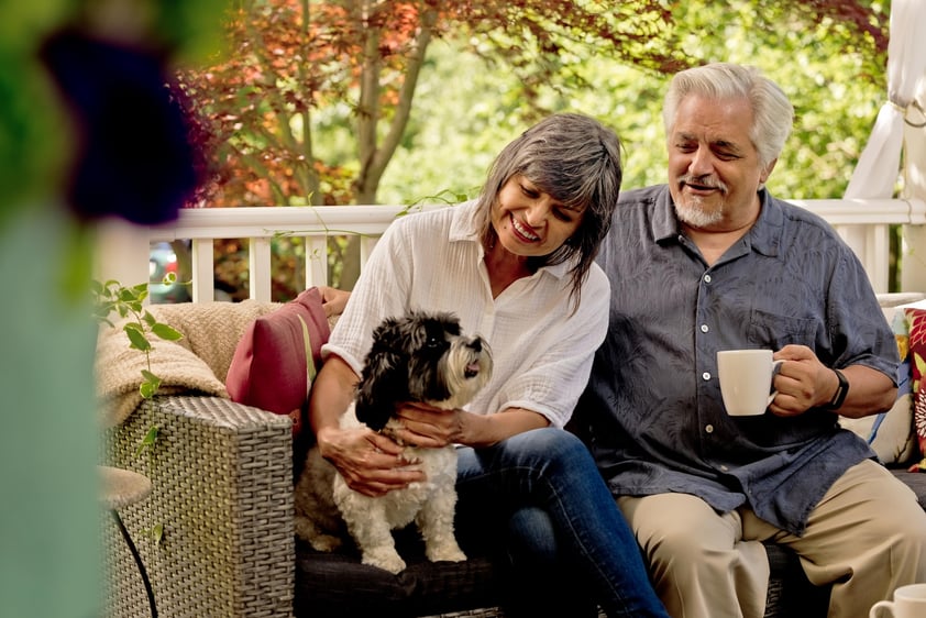 Senior couple sitting on a porch with their small dog