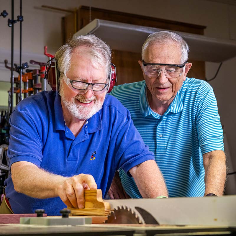 Senior men wearing safety glasses while working on a woodworking project together