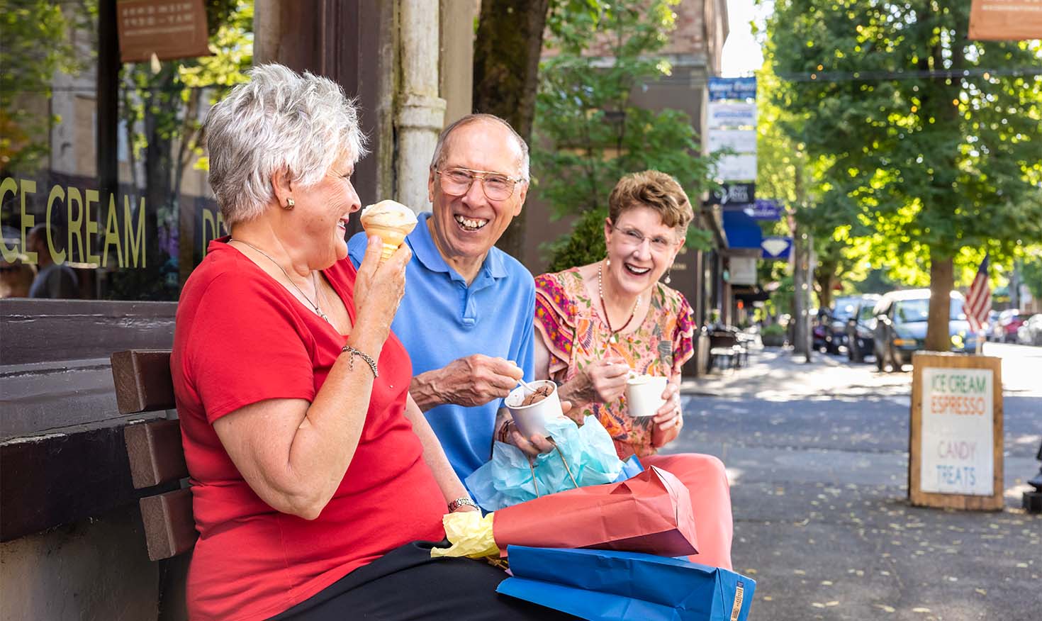 Senior friends sitting on a bench enjoying ice cream together