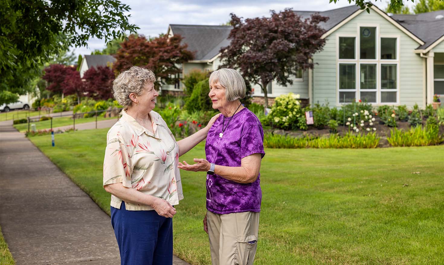 Friendly neighbors having a conversation outside on the sidewalk near their homes