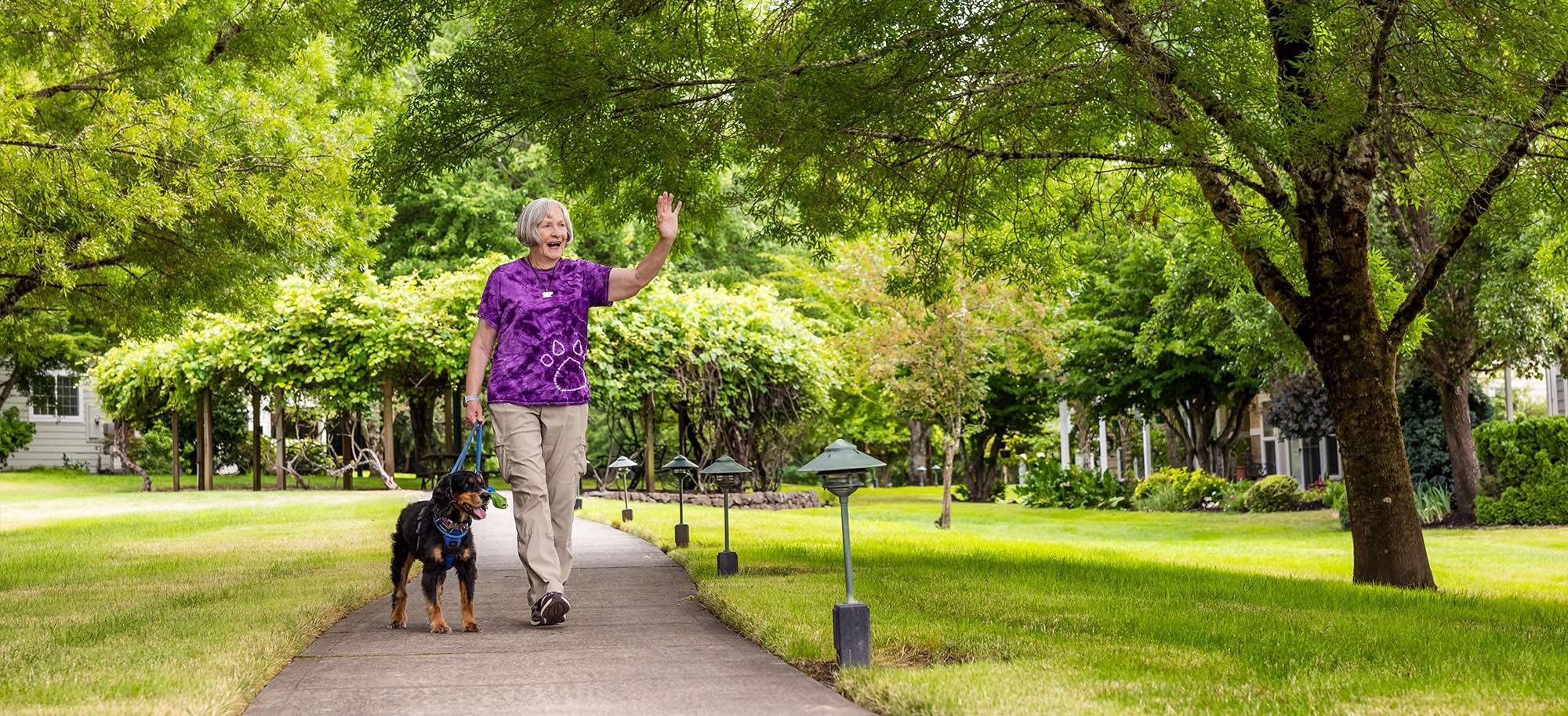 Senior woman walking her dog while smiling and waving to neighbors in McMinnville, Oregon
