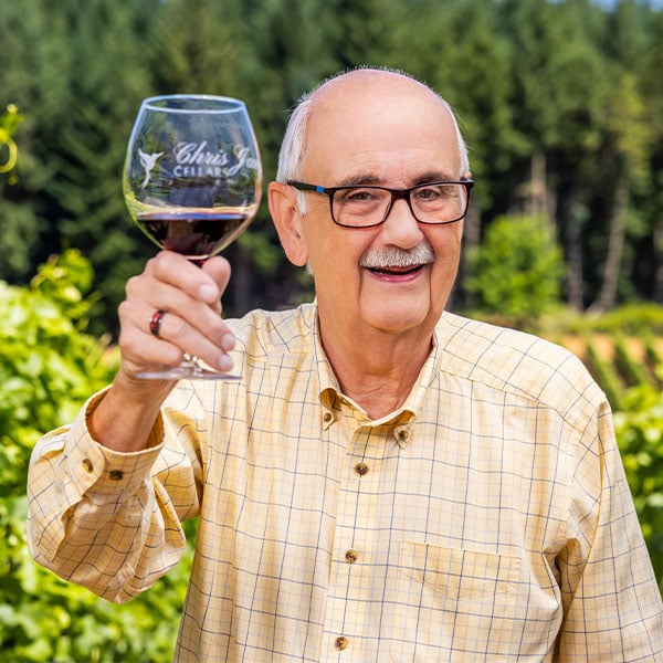 Senior man holding up a glass of red wine in a vineyard
