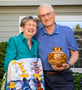 Eileen and Jim holding a quilt and wood vase