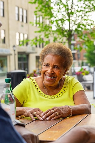 Senior woman sitting at an outdoor cafe smiling at a friend