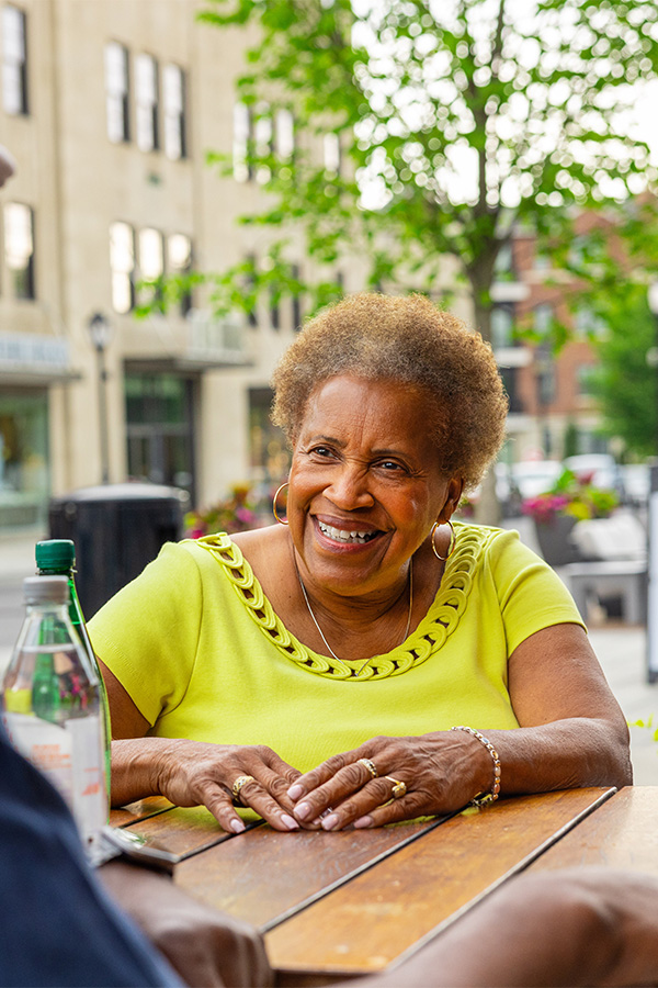 Senior woman sitting at an outdoor cafe smiling at a friend