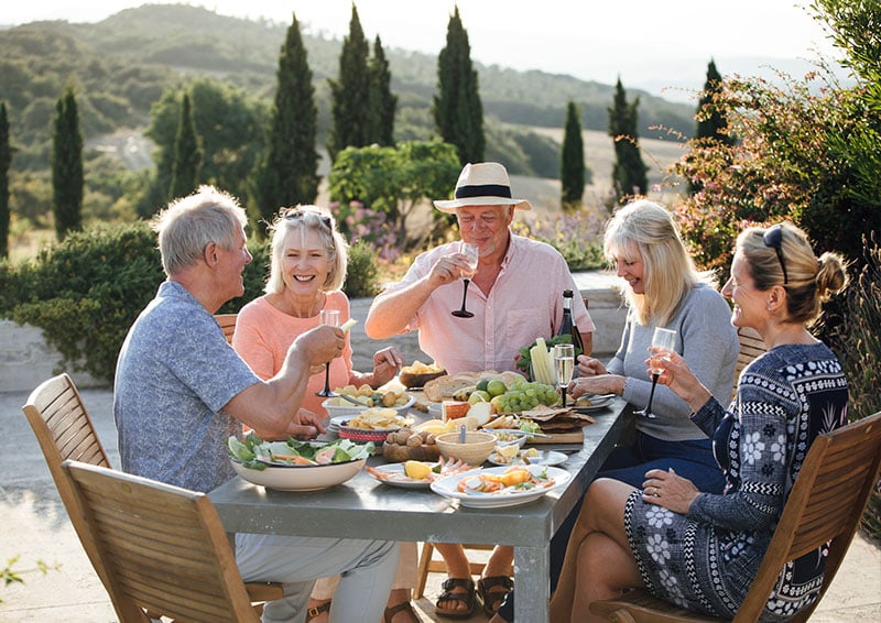 Group of seniors enjoying wine and food outdoors