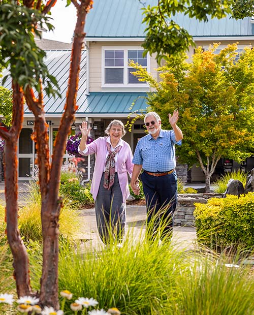 Senior couple outside holding hands and waving at camera