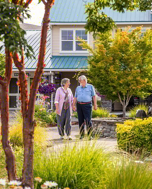 A senior couple holding hands while walking outside in a nice neighborhood