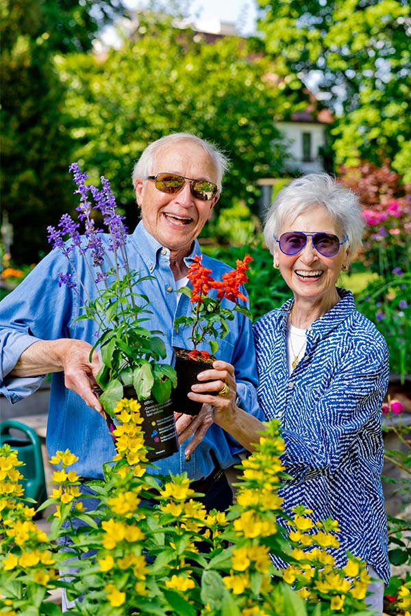 Senior couple holding up plants in a garden