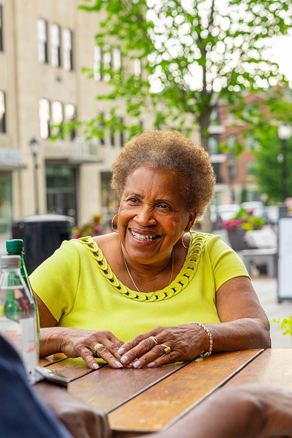 Senior woman sitting at an outdoor cafe smiling at a friend