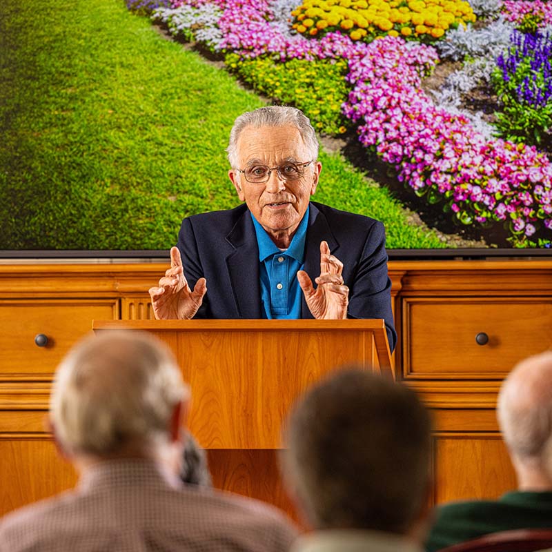 Senior man at a podium giving a lecture to a crowd of senior residents