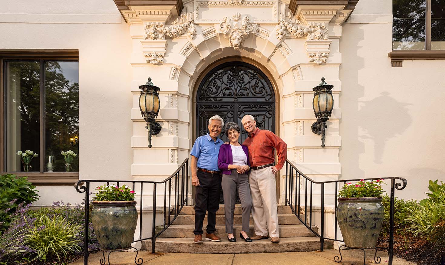 Three seniors posing on the steps outside the mansion doors