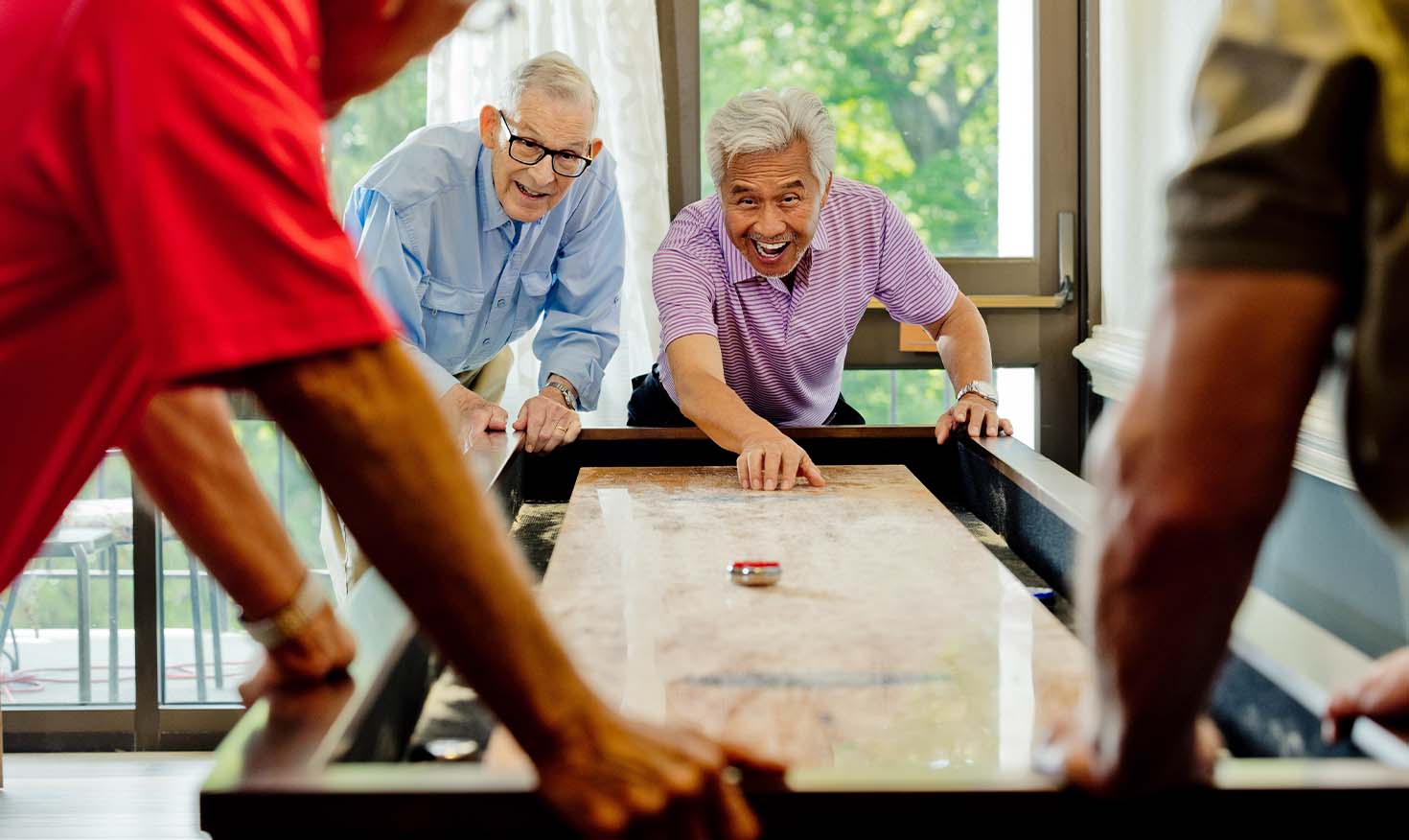 Senior friends playing table shuffleboard