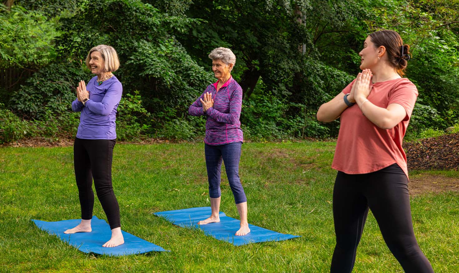 Two senior women at an outdoor yoga class with an instructor