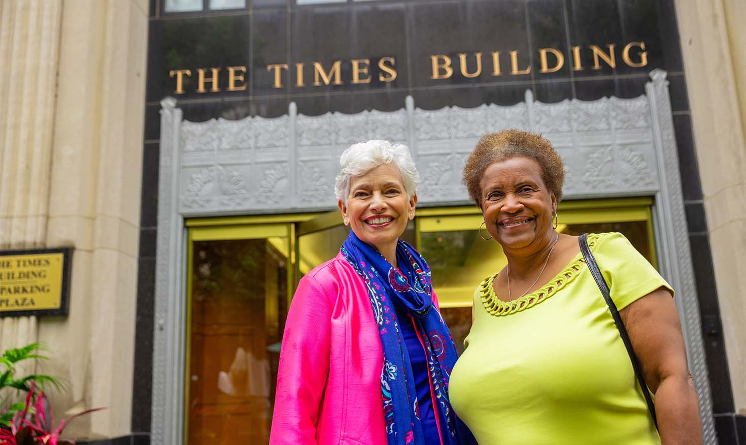 Two senior woman smiling outside The Times Building
