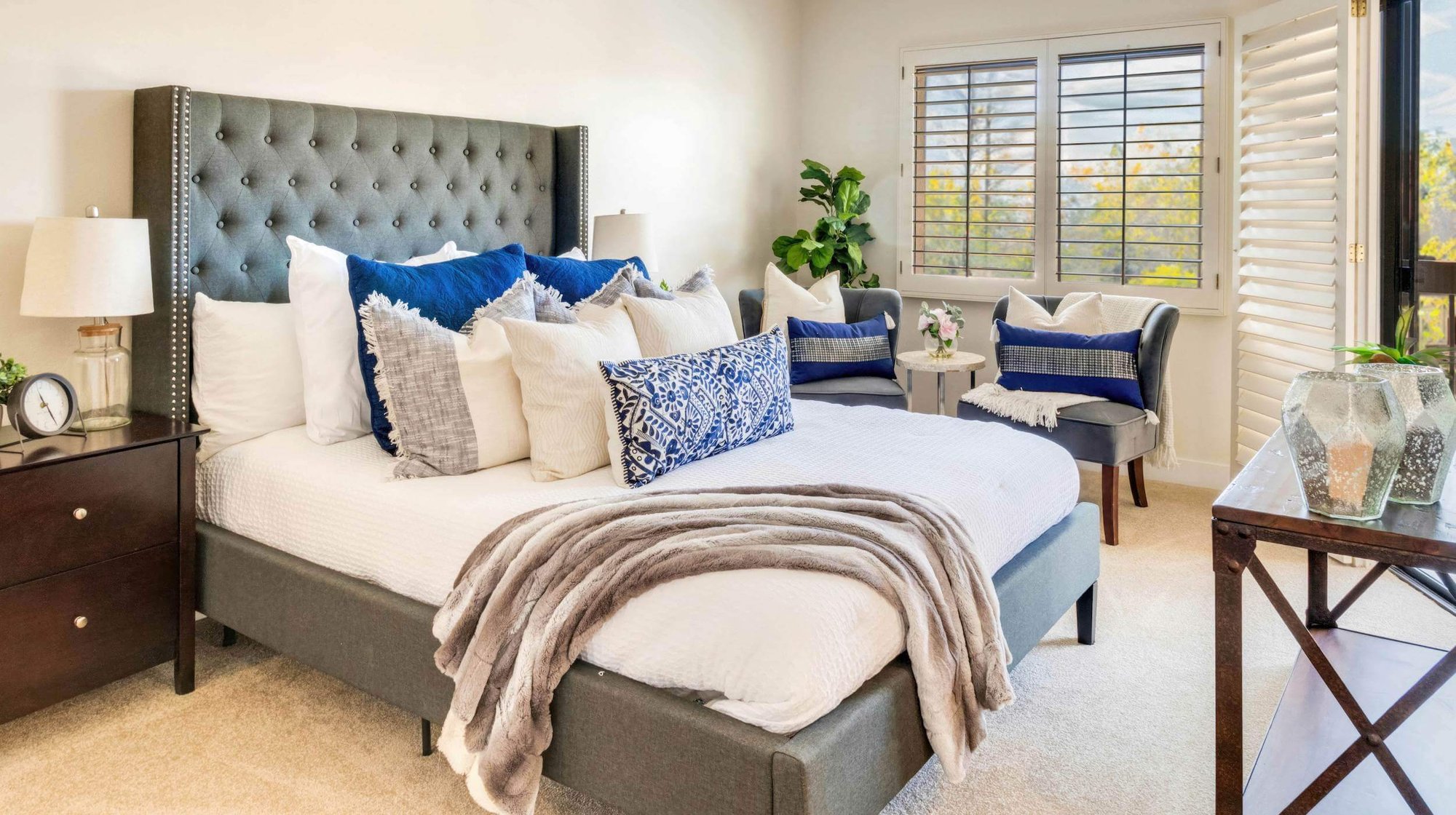 bedroom with dark grey tufted headboard and dark wood accent furniture