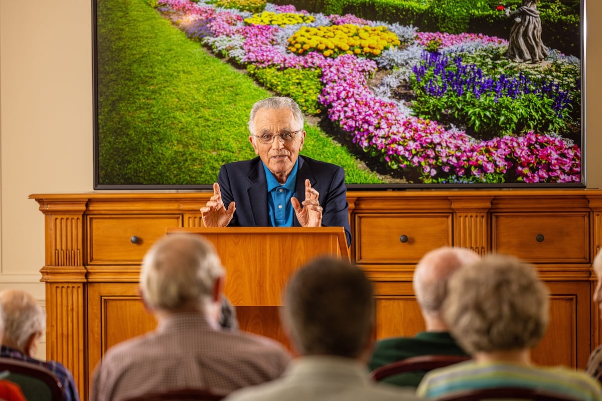 Senior man at a podium giving a lecture to a crowd of senior residents