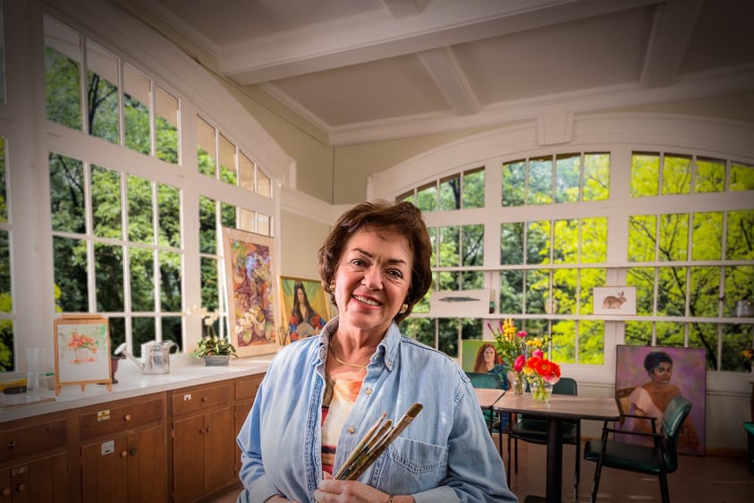 Senior woman holding paintbrushes in art studio