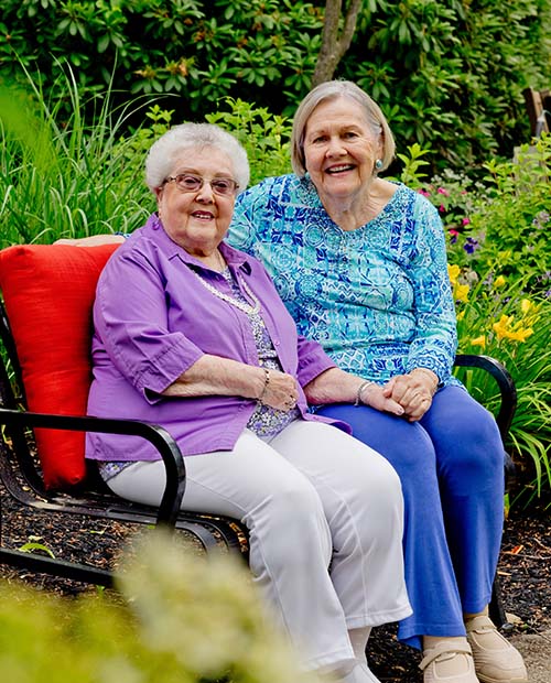 Two senior women sitting on a bench outside