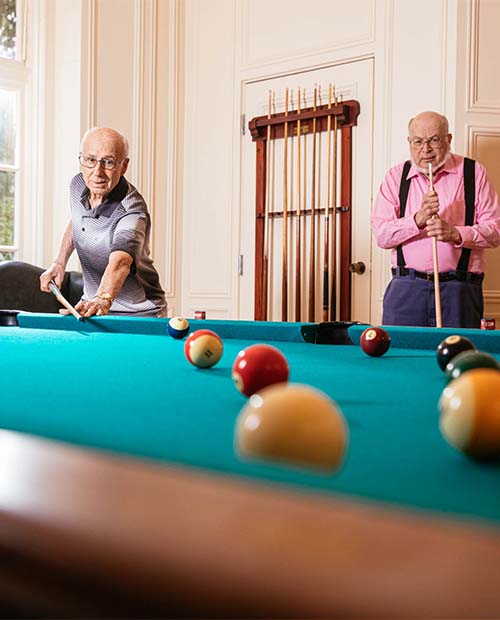 Two senior men playing a game of pool