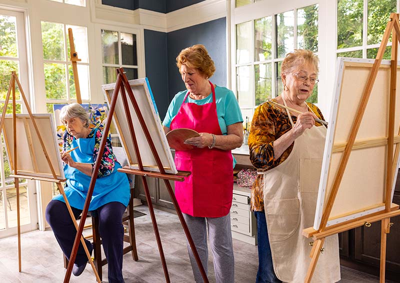 Three senior women painting on easels