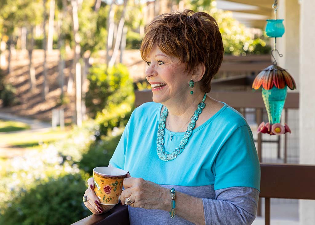 senior woman enjoying a cup of coffee on her outdoor balcony