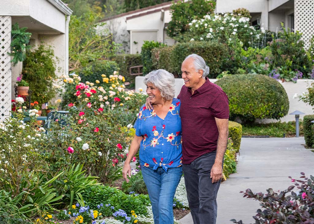 a senior couple walking through a garden courtyard