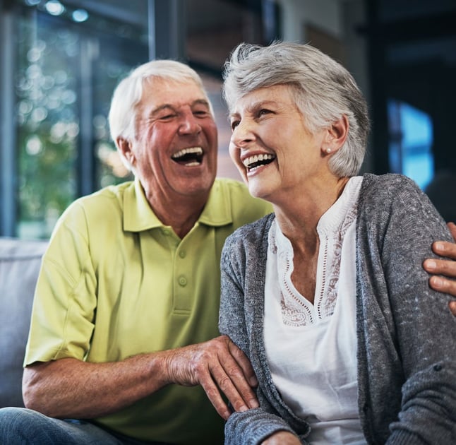 smiling senior couple sitting on couch 