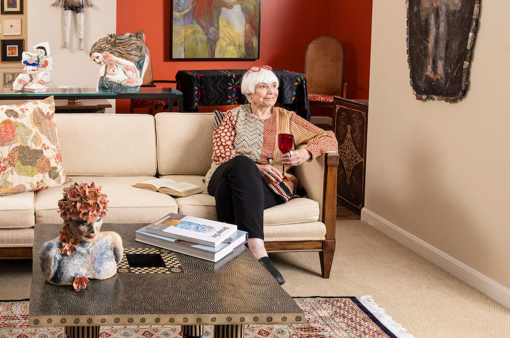 Senior woman sitting on a couch in living room holding a glass of wine