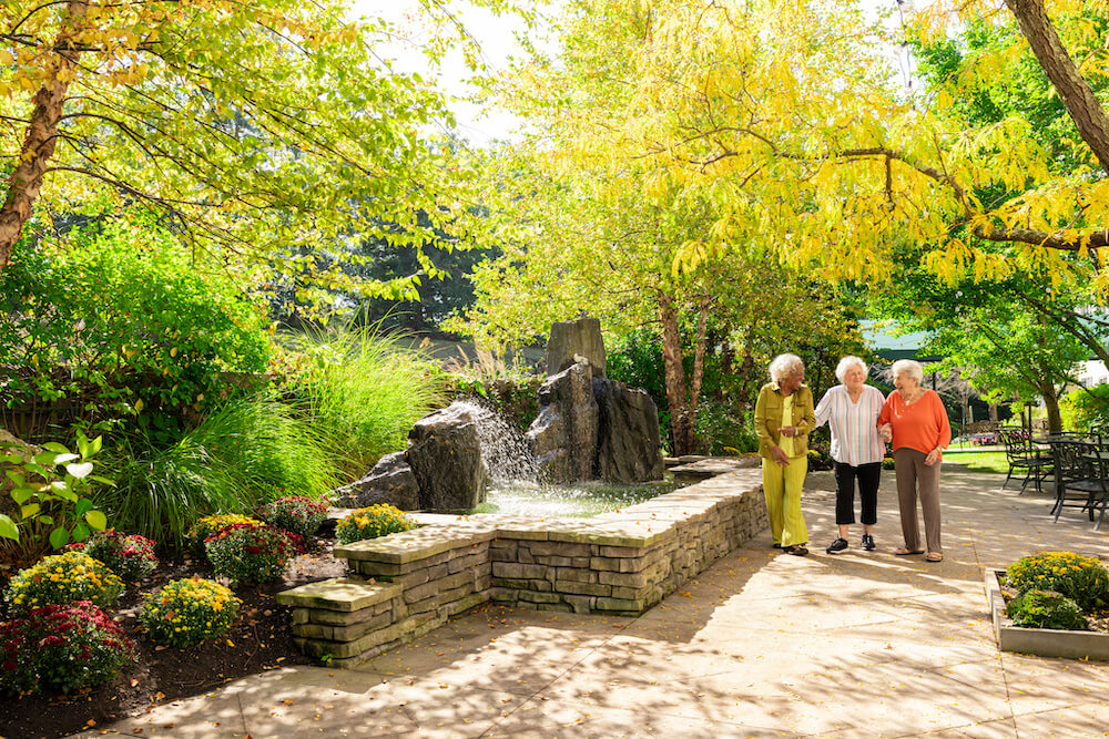 Group of three senior women walking on a patio near a waterfall