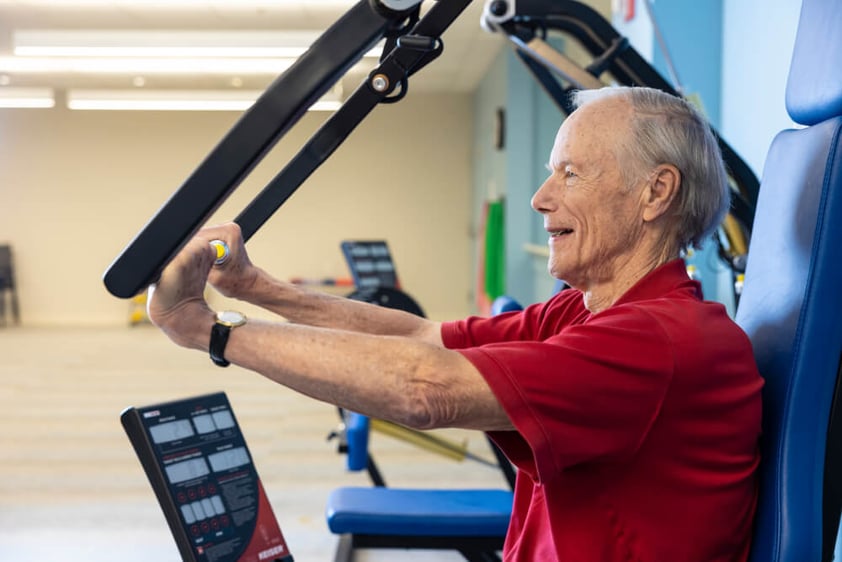 Senior man using a weight machine at the gym
