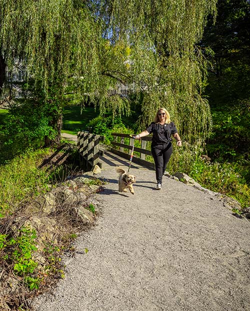 Woman walking a small dog on the walking path outside Springhouse