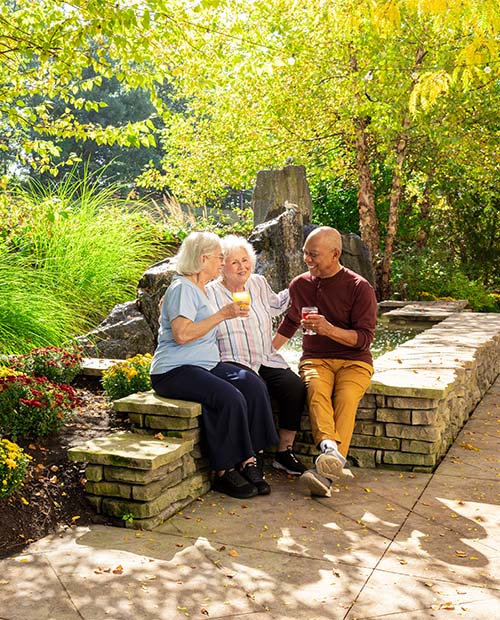 Three senior friends enjoying beverages in an outdoor garden