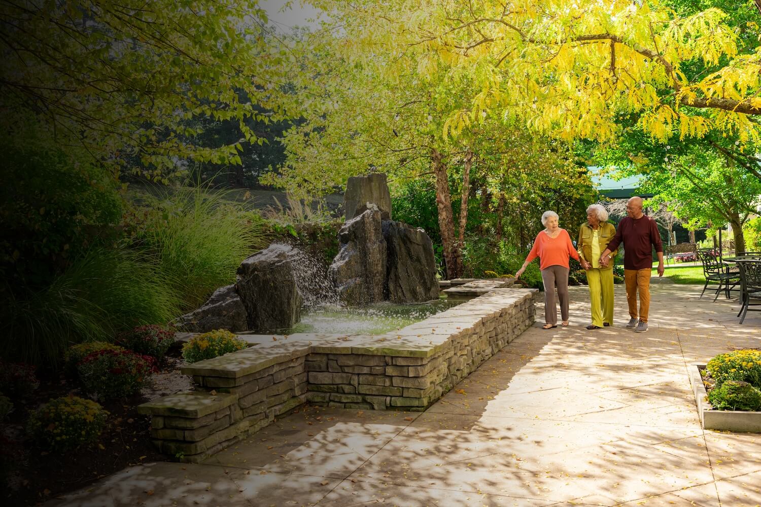 three seniors walking next to outdoor fountain