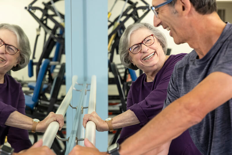 Senior woman working out with trainer in fitness center