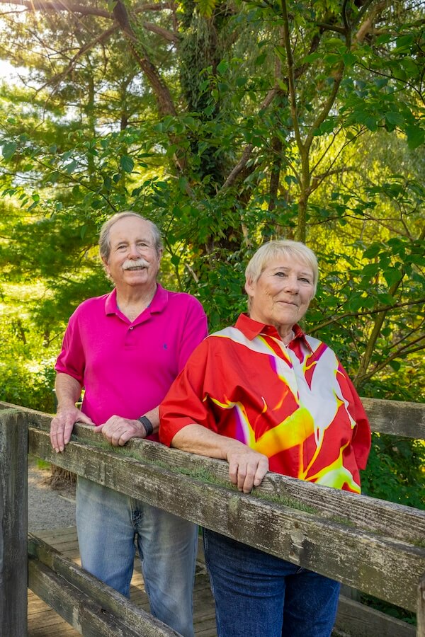 Smiling senior couple on walking path bridge enjoying nature